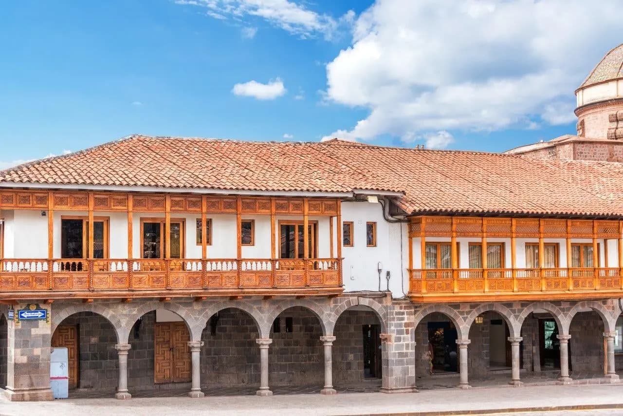 A colonial arcade with carved wooden balconies on a Cusco square
