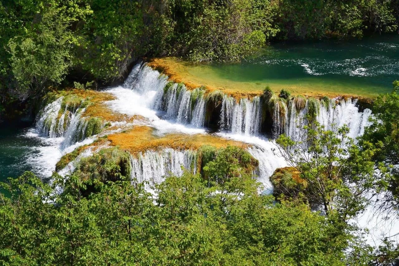 White cascades through green woodland at Krka, seen from above