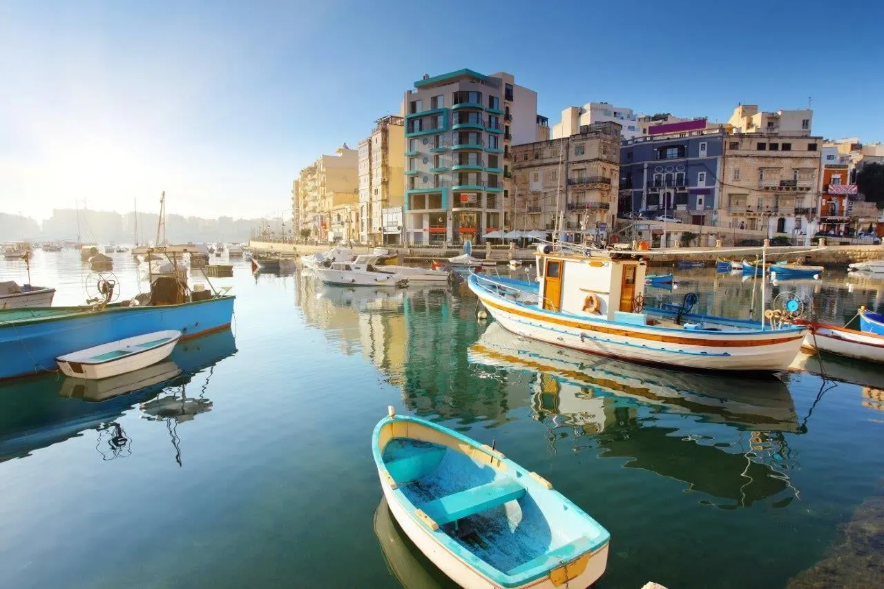 Small fishing boats on a calm bay lined with apartment buildings