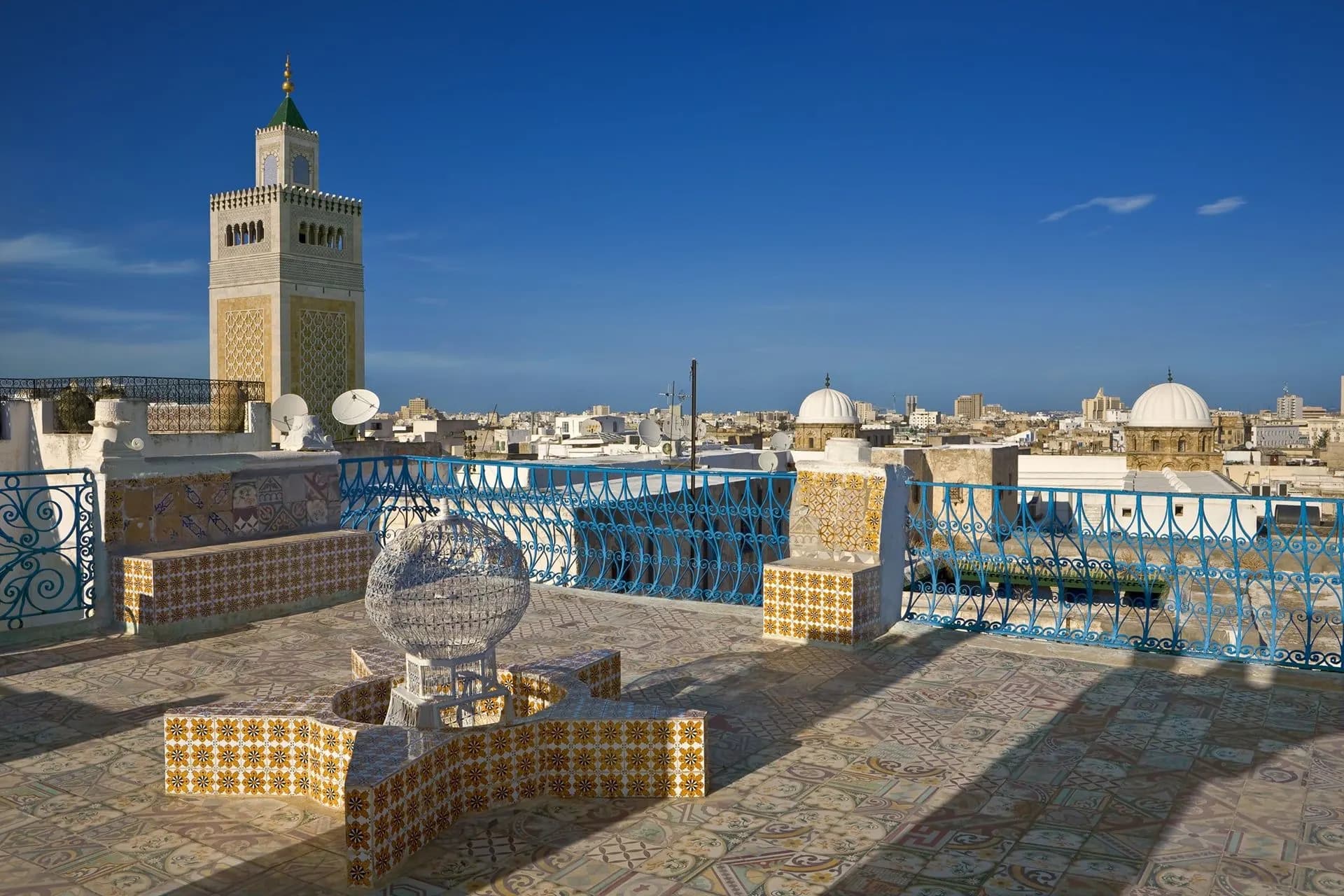 Medina rooftops and domes of Tunis below a square stone minaret
