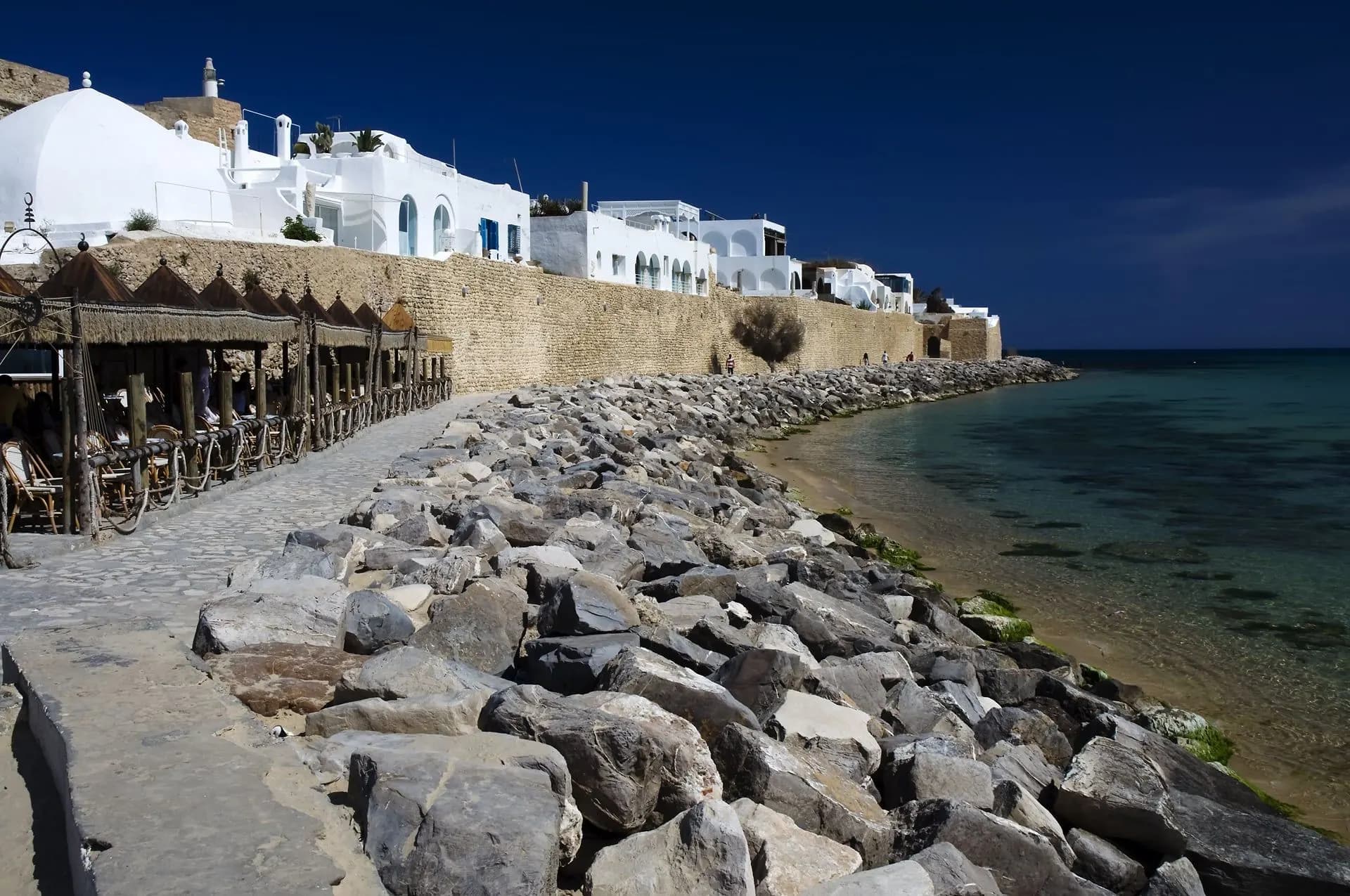White houses along a rocky shore and old sea wall at dusk