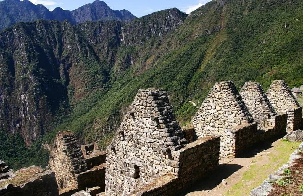 Gabled stone houses at Machu Picchu above a deep green valley