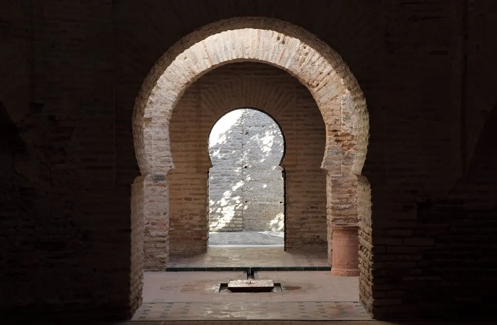 A brick horseshoe arch opening onto a sunlit wall