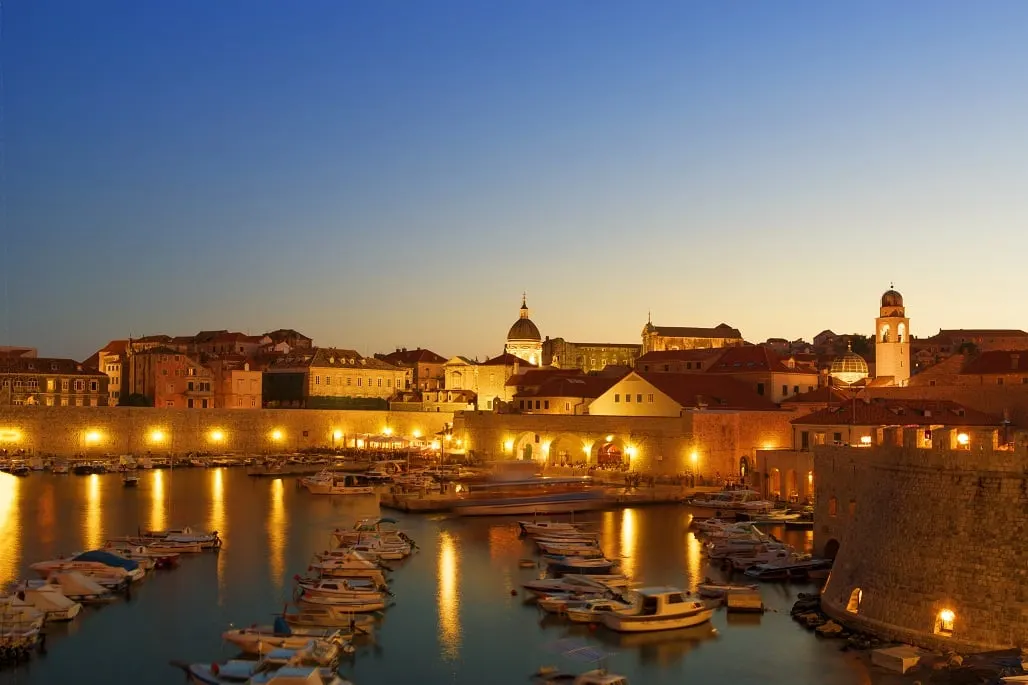 Lights along Dubrovnik's old port and city walls at dusk