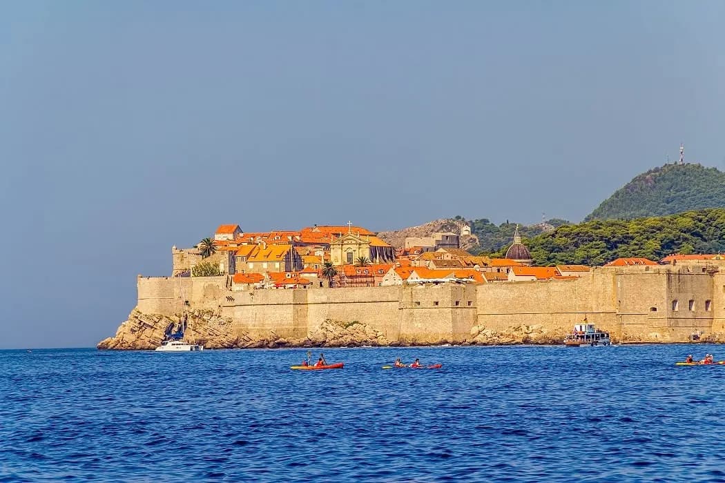 Dubrovnik's sea walls seen across the water, with kayaks below