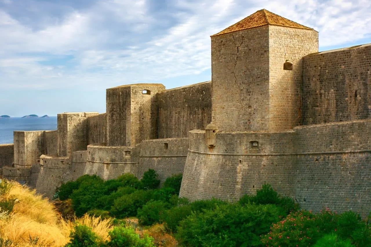 A square stone tower on Dubrovnik's city walls above green scrub