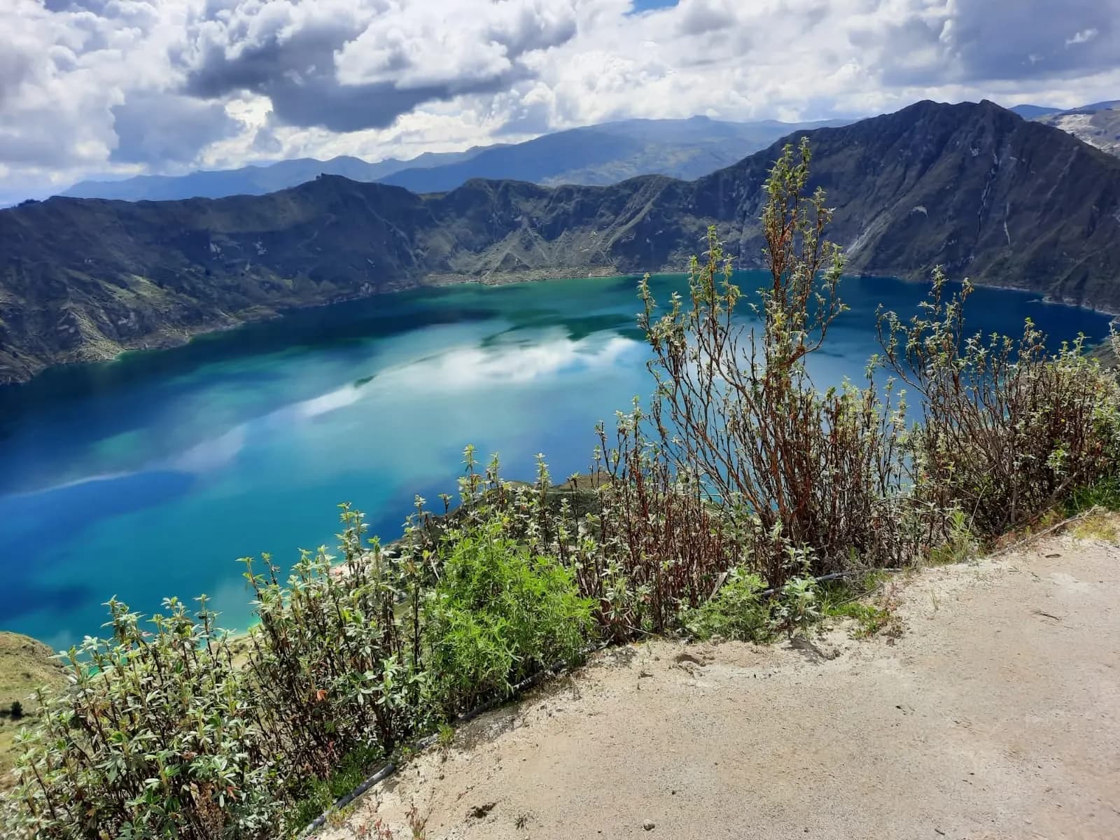 The blue crater lake of Quilotoa ringed by volcanic slopes