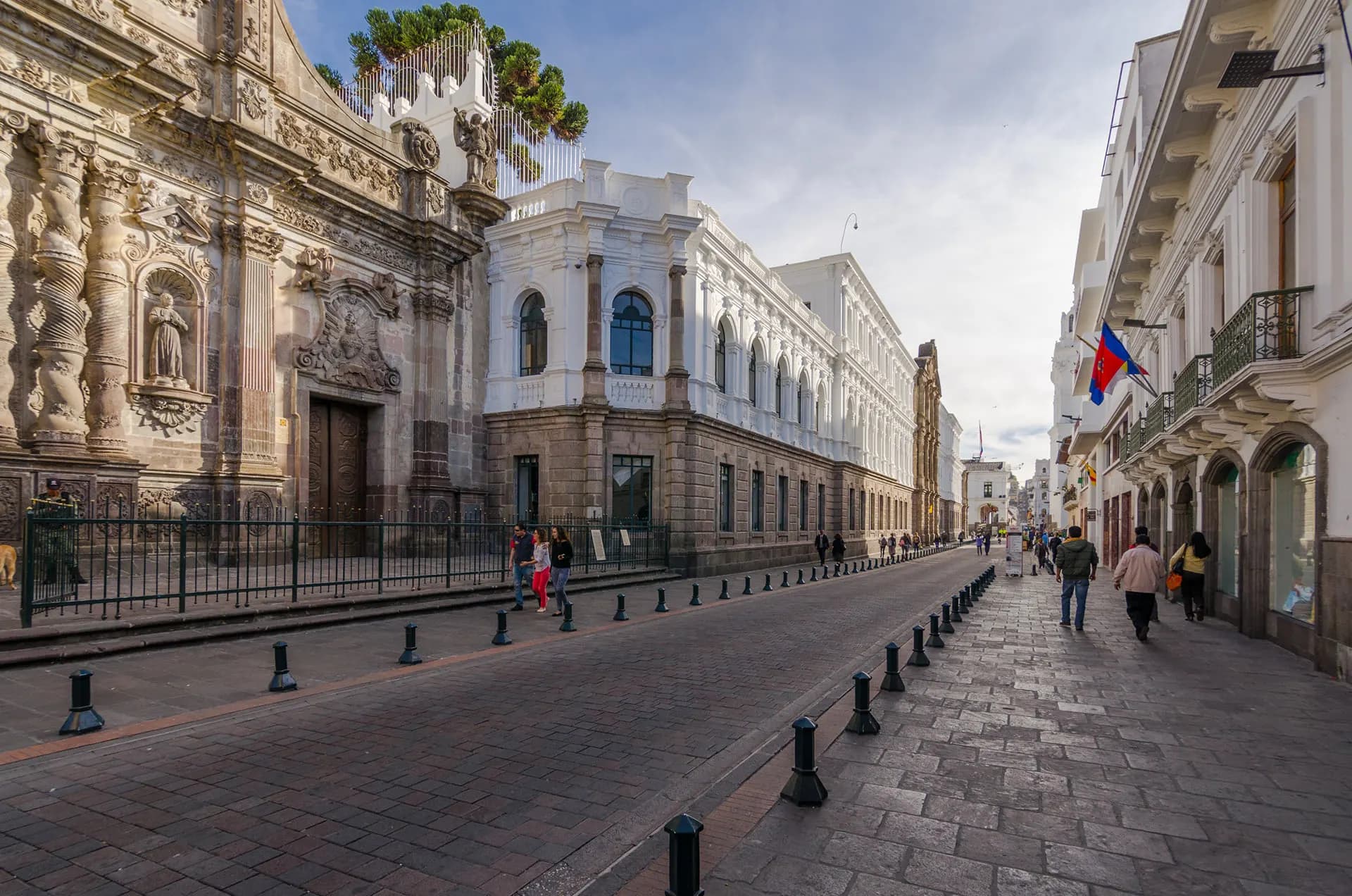 A cobbled street of white colonial buildings beside a carved church