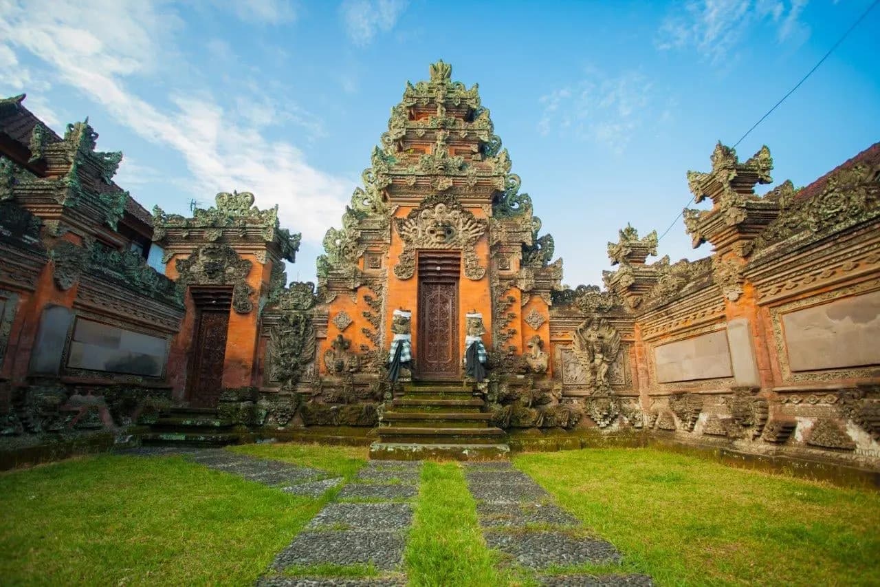 A carved red-brick Balinese temple gateway at the end of a stone path
