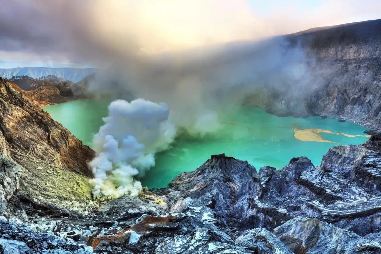 The turquoise crater lake of Ijen with sulphur steam rising from its shore