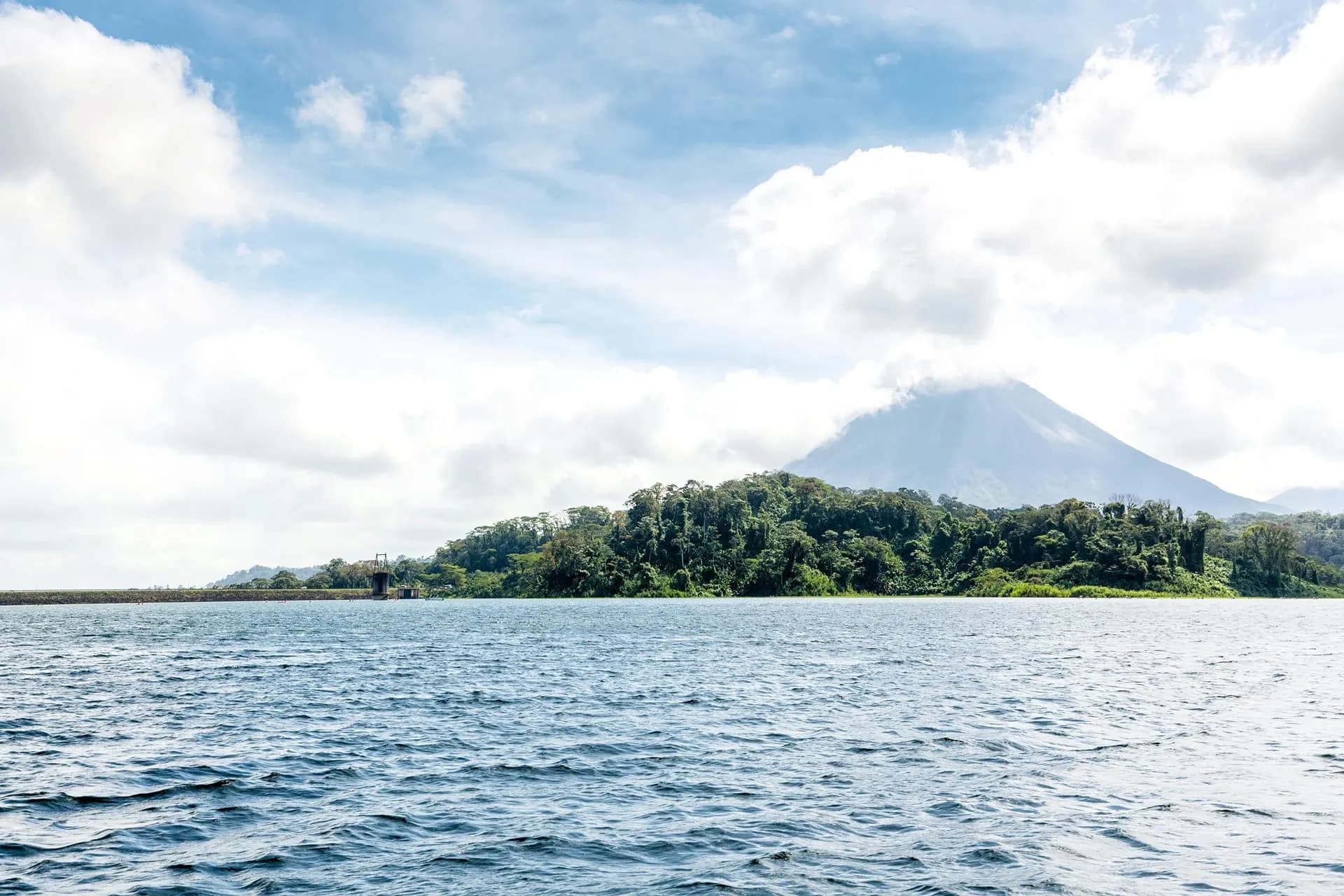 Arenal Volcano rising behind a forested shore across the lake