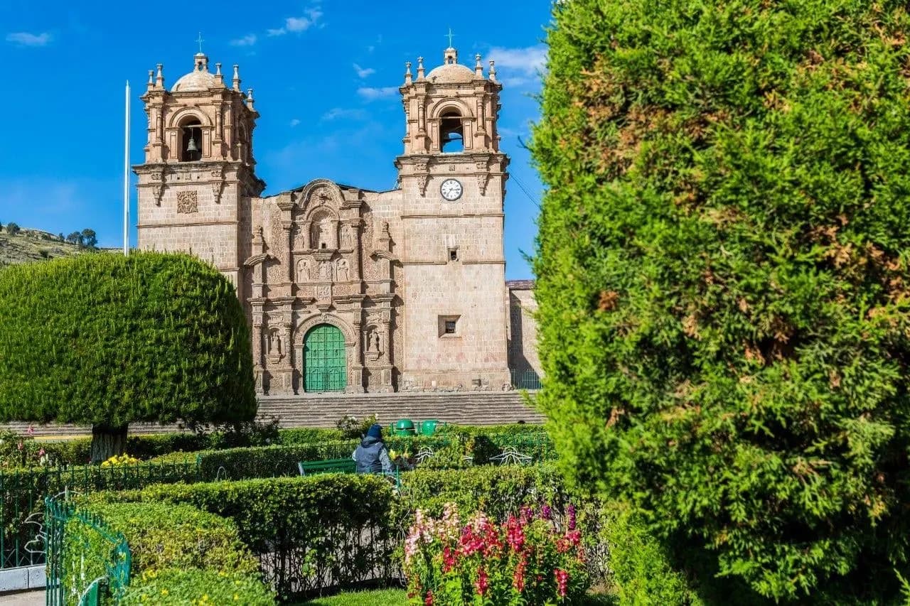 A colonial stone church with twin bell towers behind a garden