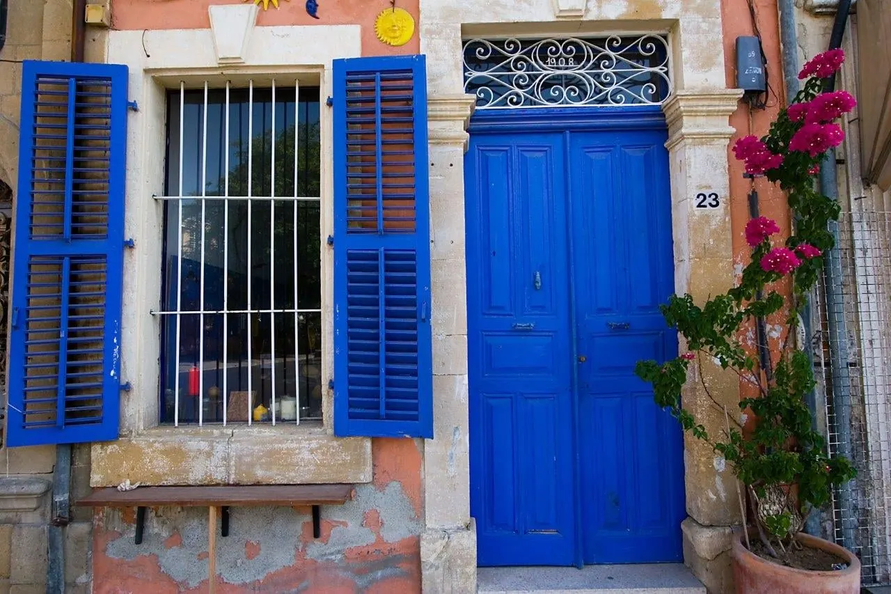 A blue door and shutters beside pink bougainvillea on an old stone house