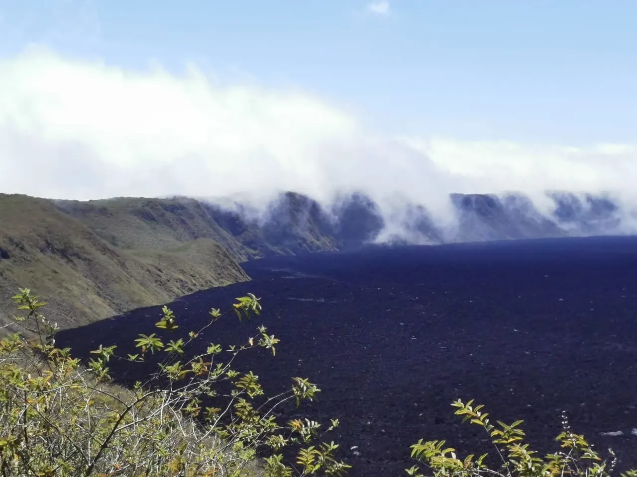 Cloud spilling over the rim of a wide volcanic crater