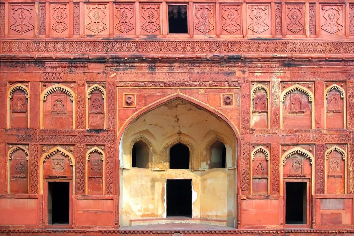 A carved red sandstone palace facade with an arched doorway