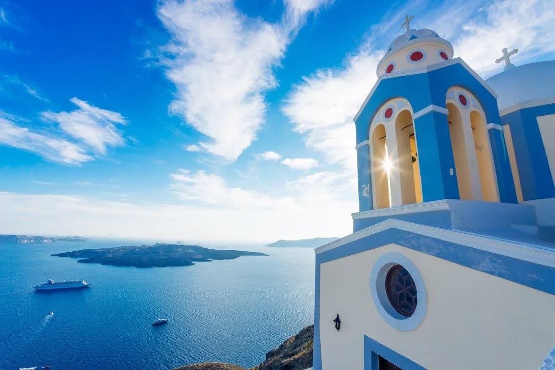 A blue and white bell tower looking over the caldera