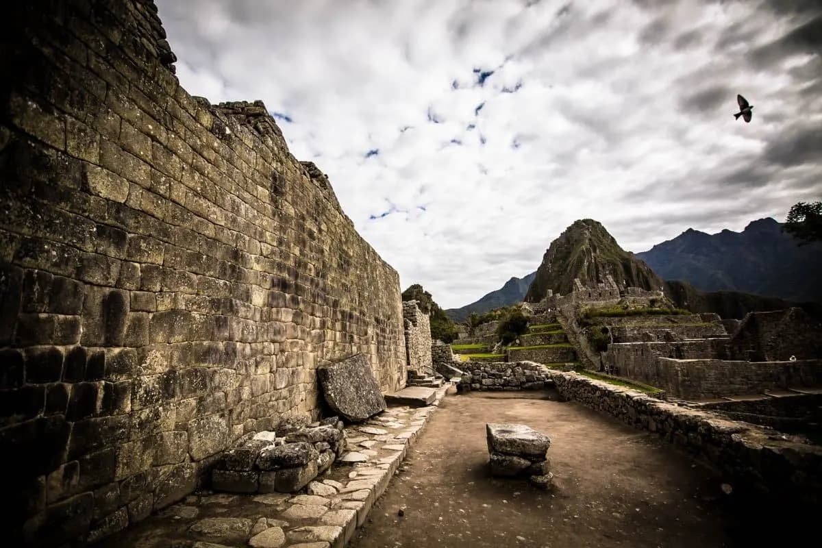 Inca stone walls and a path at Machu Picchu under a cloudy sky