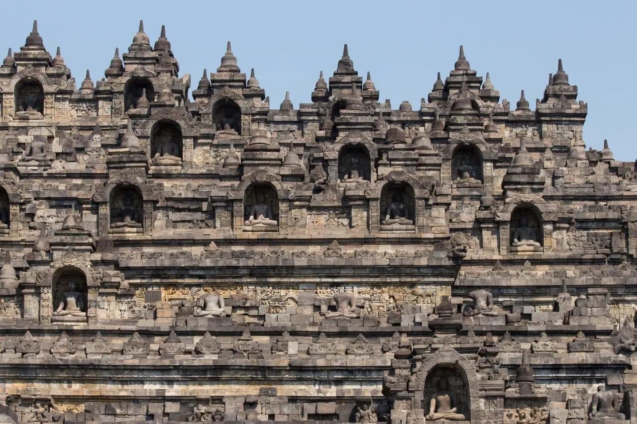 Rows of stone Buddhas in carved niches on the terraces of Borobudur