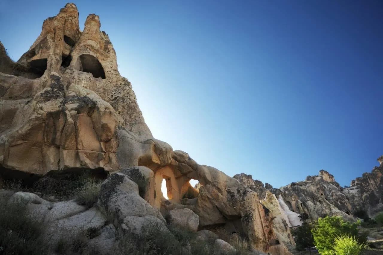 Weathered rock formations with carved openings under a clear sky