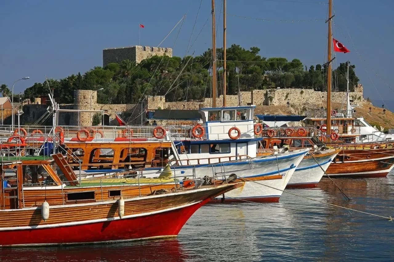 Wooden boats moored in a harbour below a hilltop castle