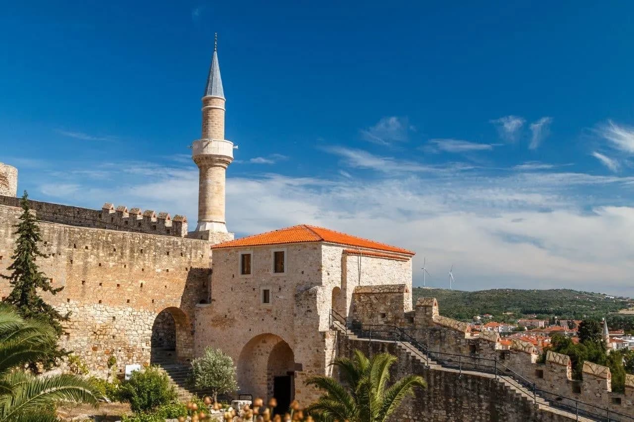 Old stone walls and a minaret under a blue sky on the Aegean coast