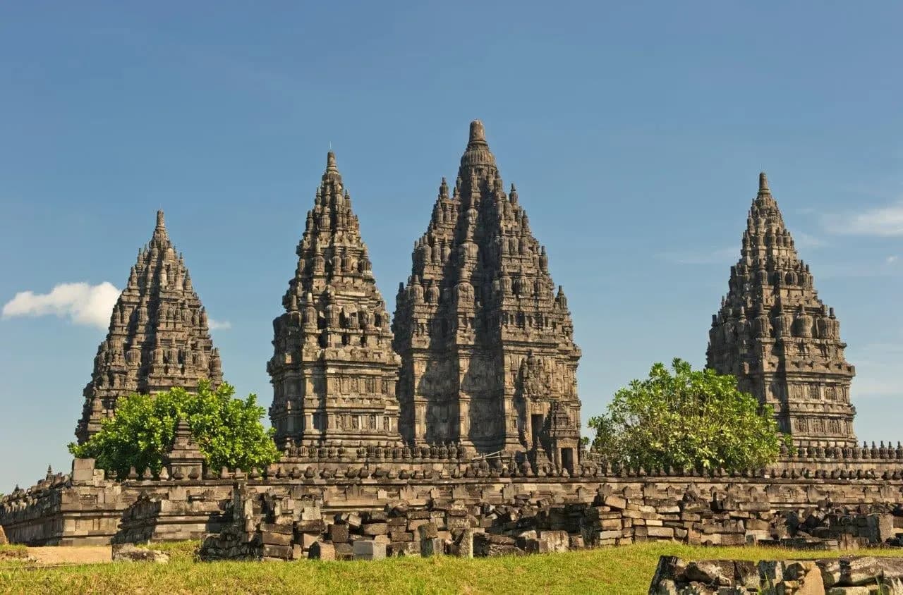 The tall carved stone spires of the Prambanan temples under a blue sky