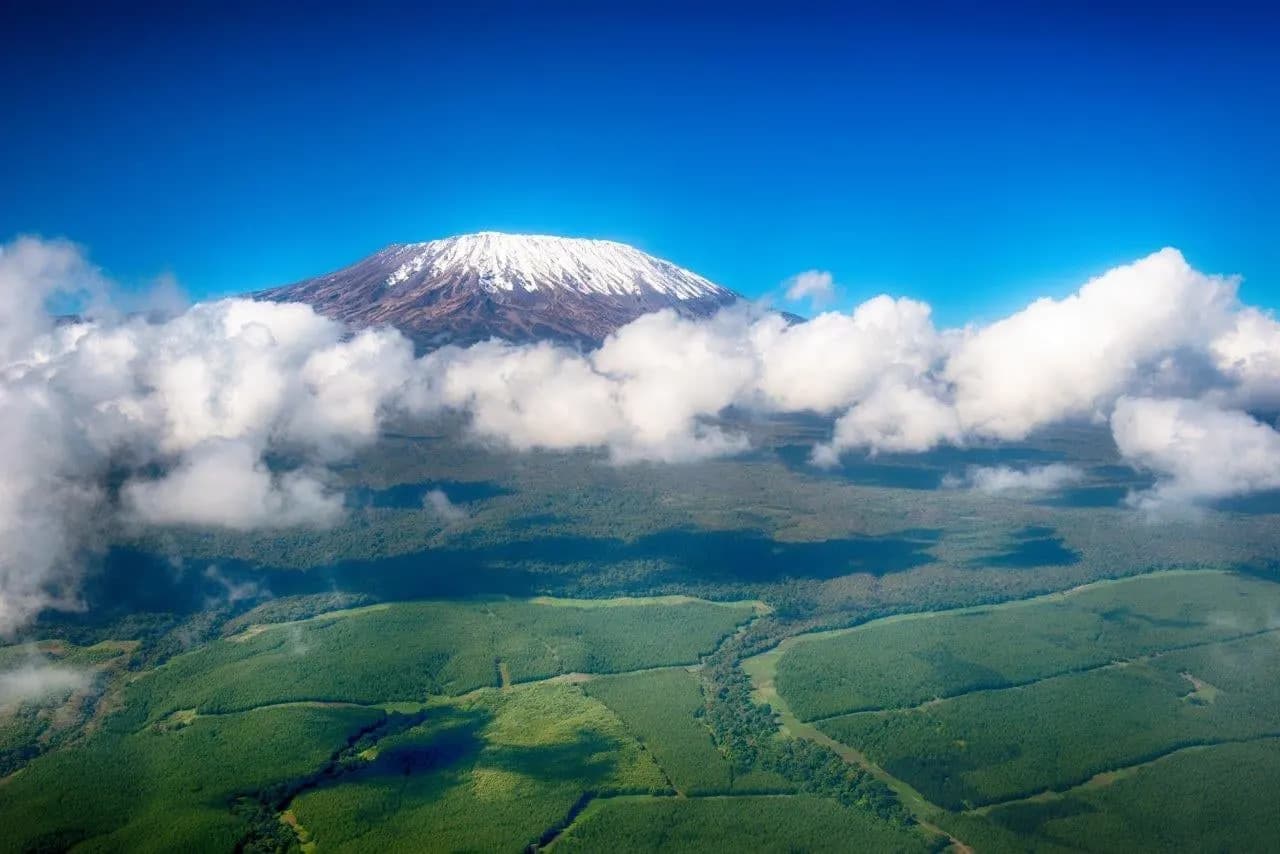 Kilimanjaro’s summit above a band of cloud and green plains
