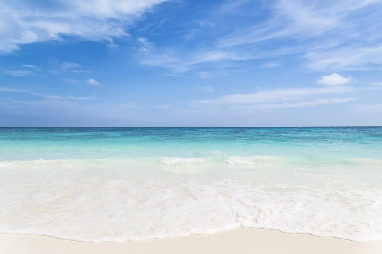 Gentle surf on a wide white-sand beach under a blue sky