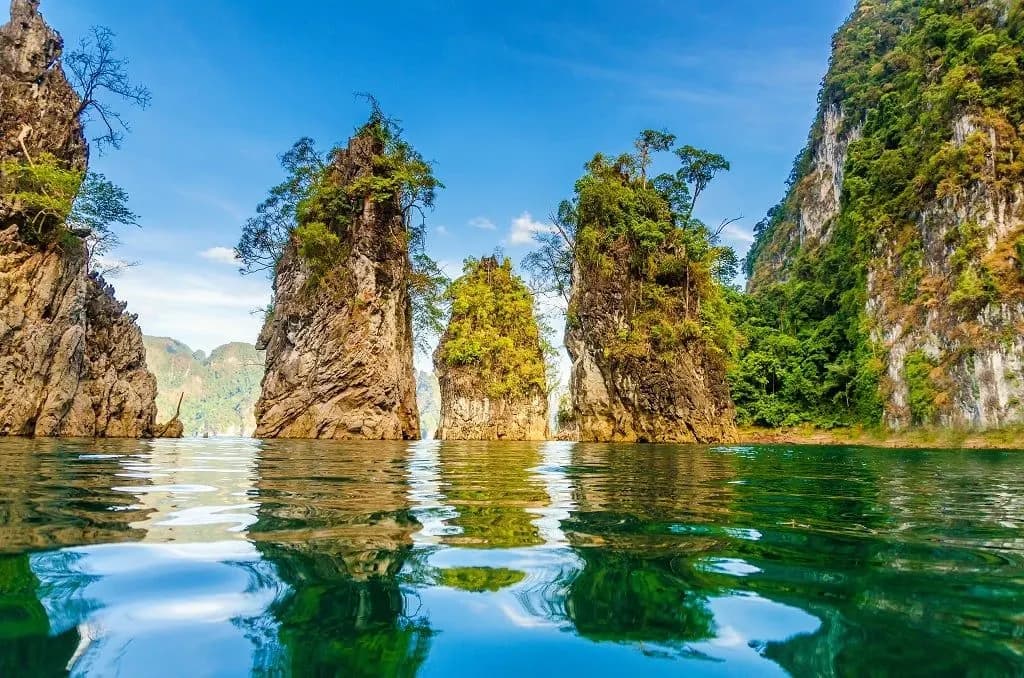 Three limestone pillars rising from the green water of Cheow Lan Lake
