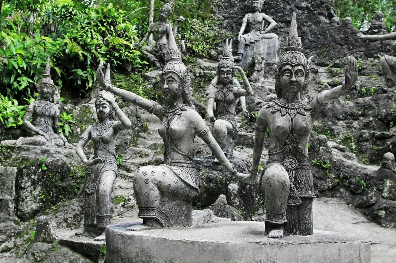 Stone figures of dancers among the trees in a hillside garden on Koh Samui