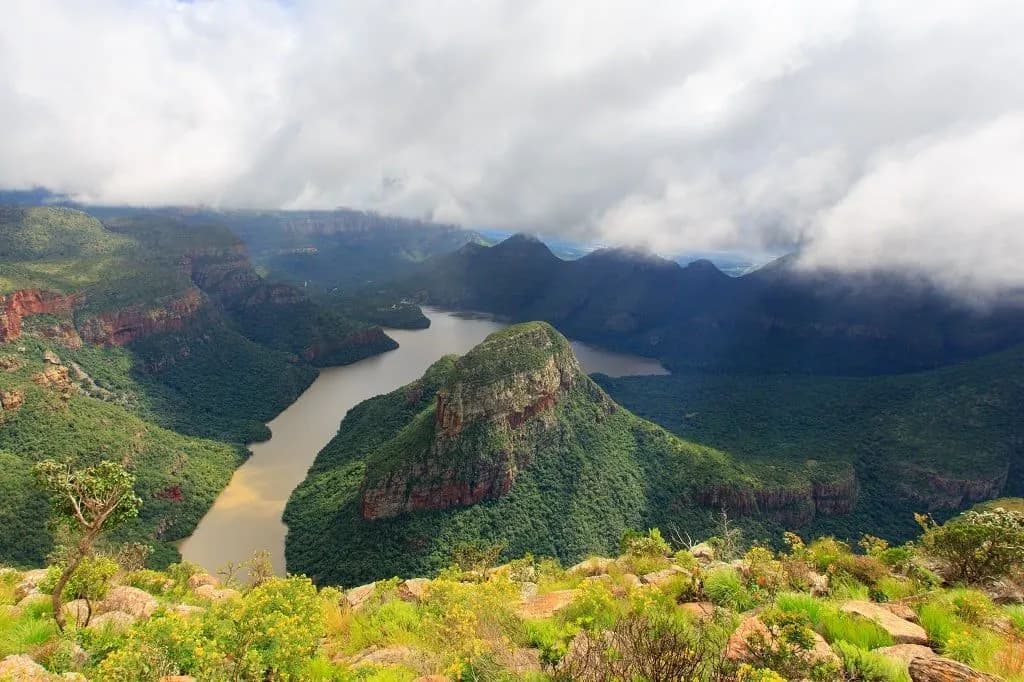 Blyde River Canyon with the river winding between green cliffs under low cloud