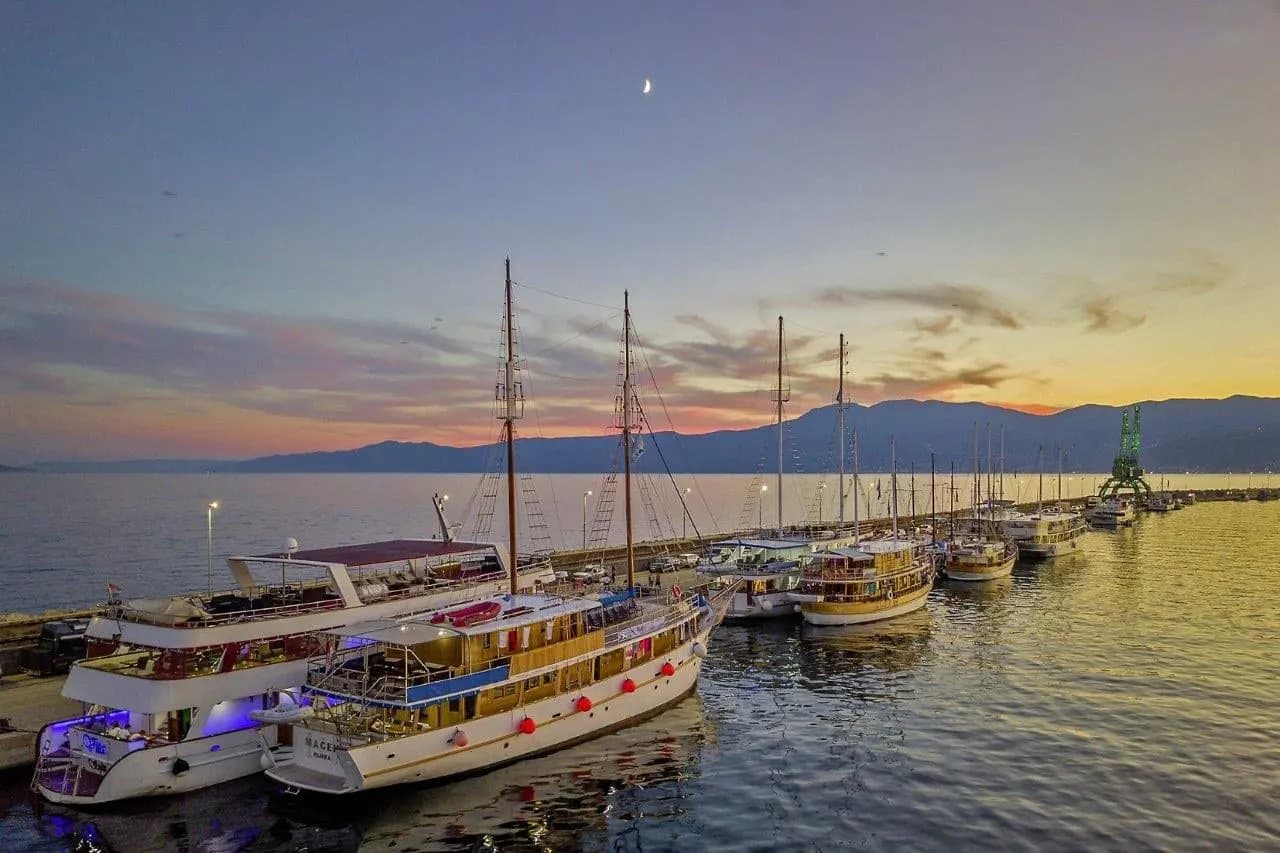 Cruise boats moored along a harbour wall at sunset