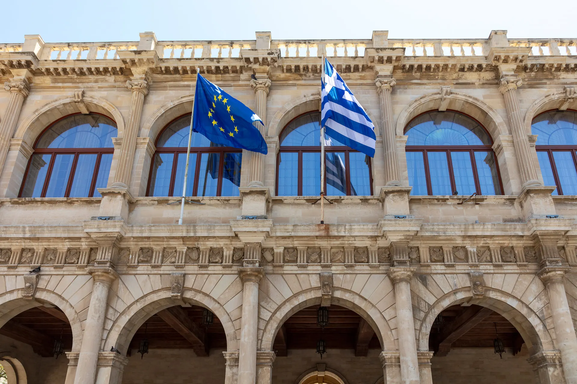 The arcaded Venetian loggia in Heraklion with Greek and European flags