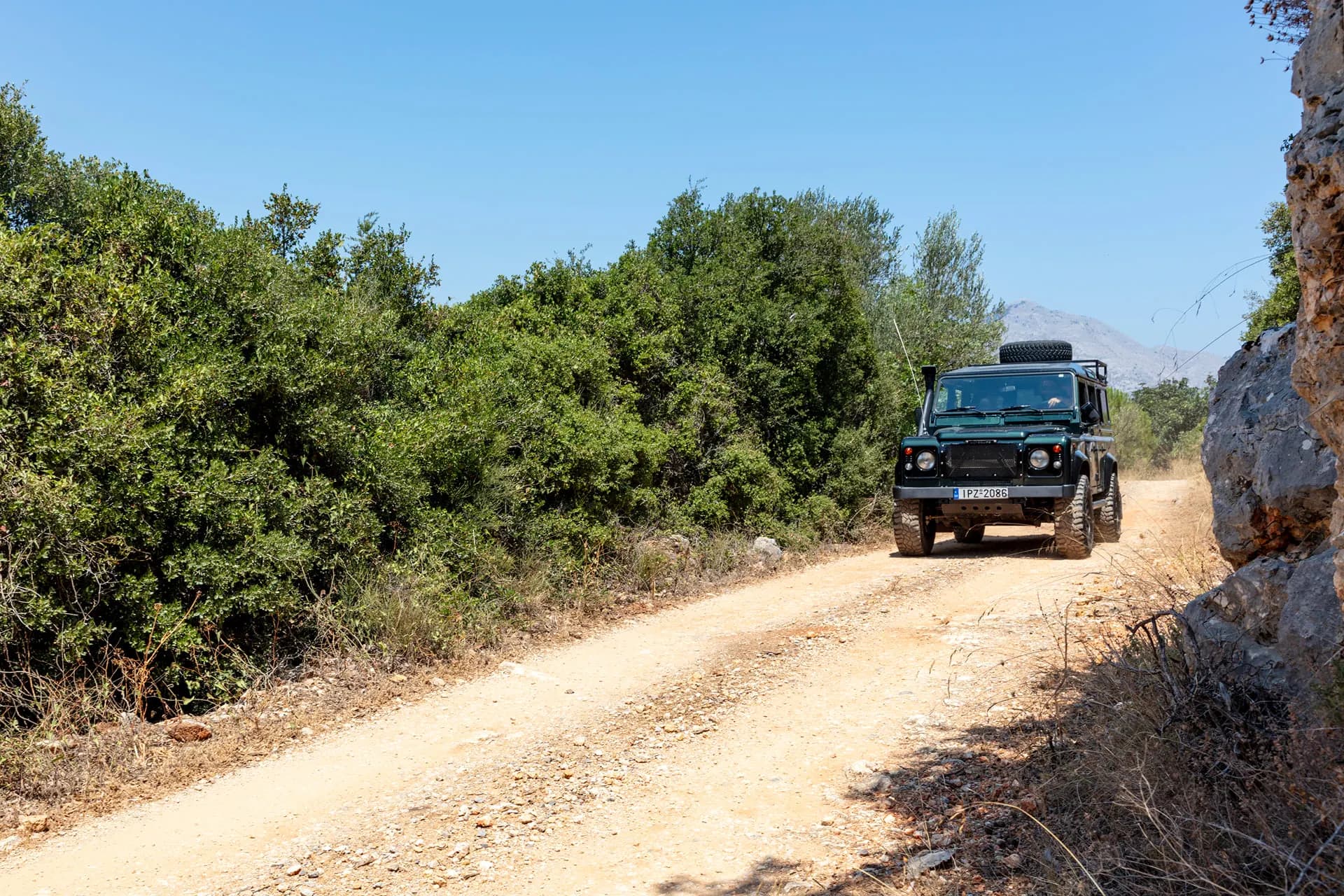 A Land Rover on a dirt track through Cretan scrub