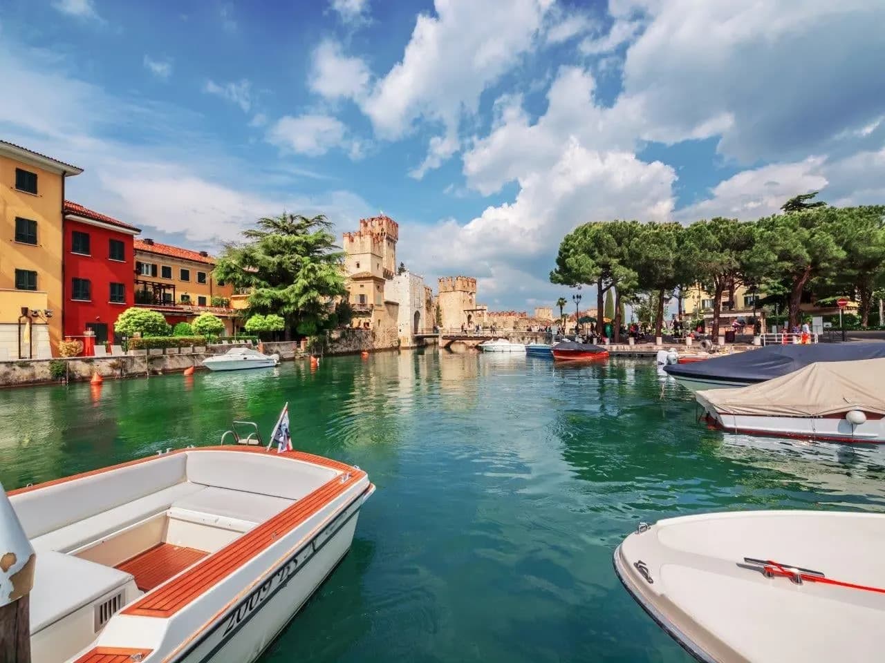Motorboats moored in Sirmione's harbour below the castle towers