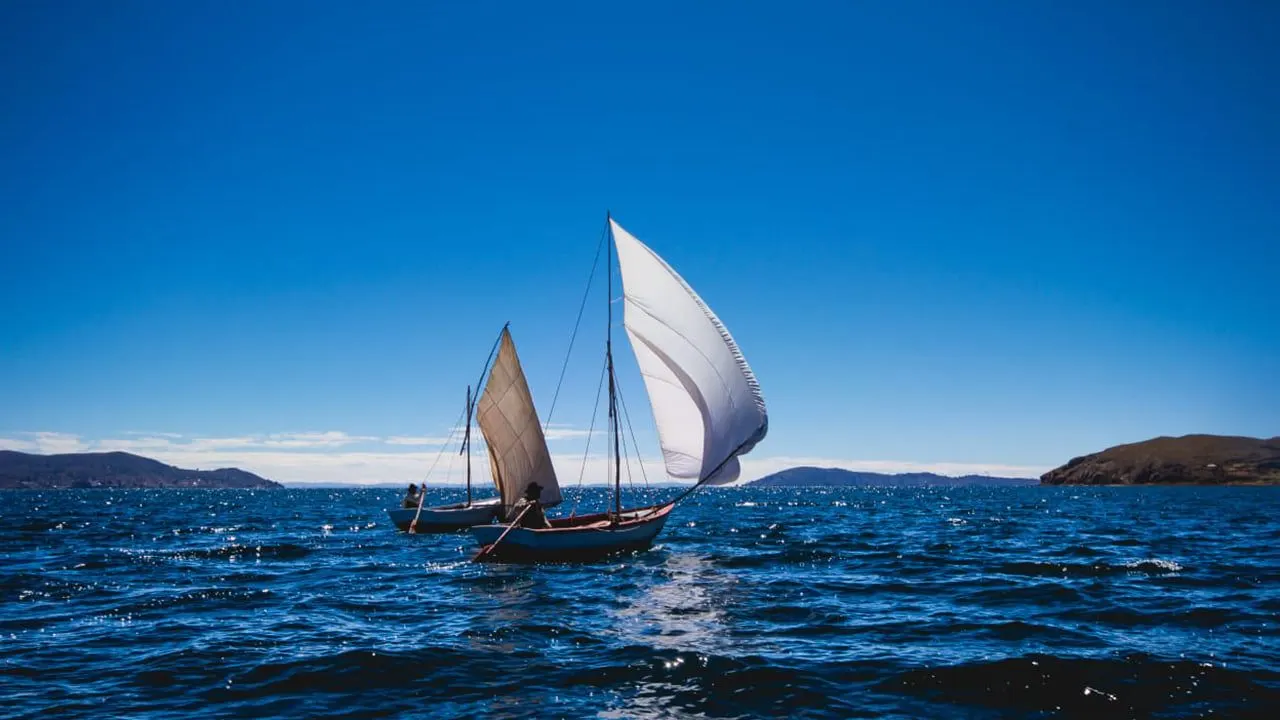 Two small sailing boats on the deep blue water of Lake Titicaca