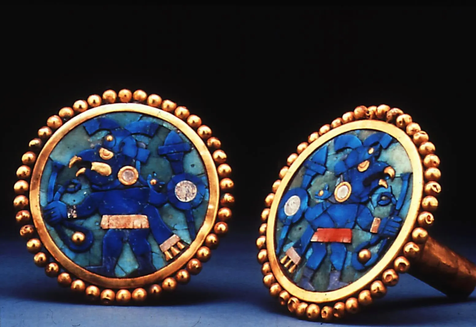 A pair of pre-Columbian gold ear ornaments inlaid with blue stone