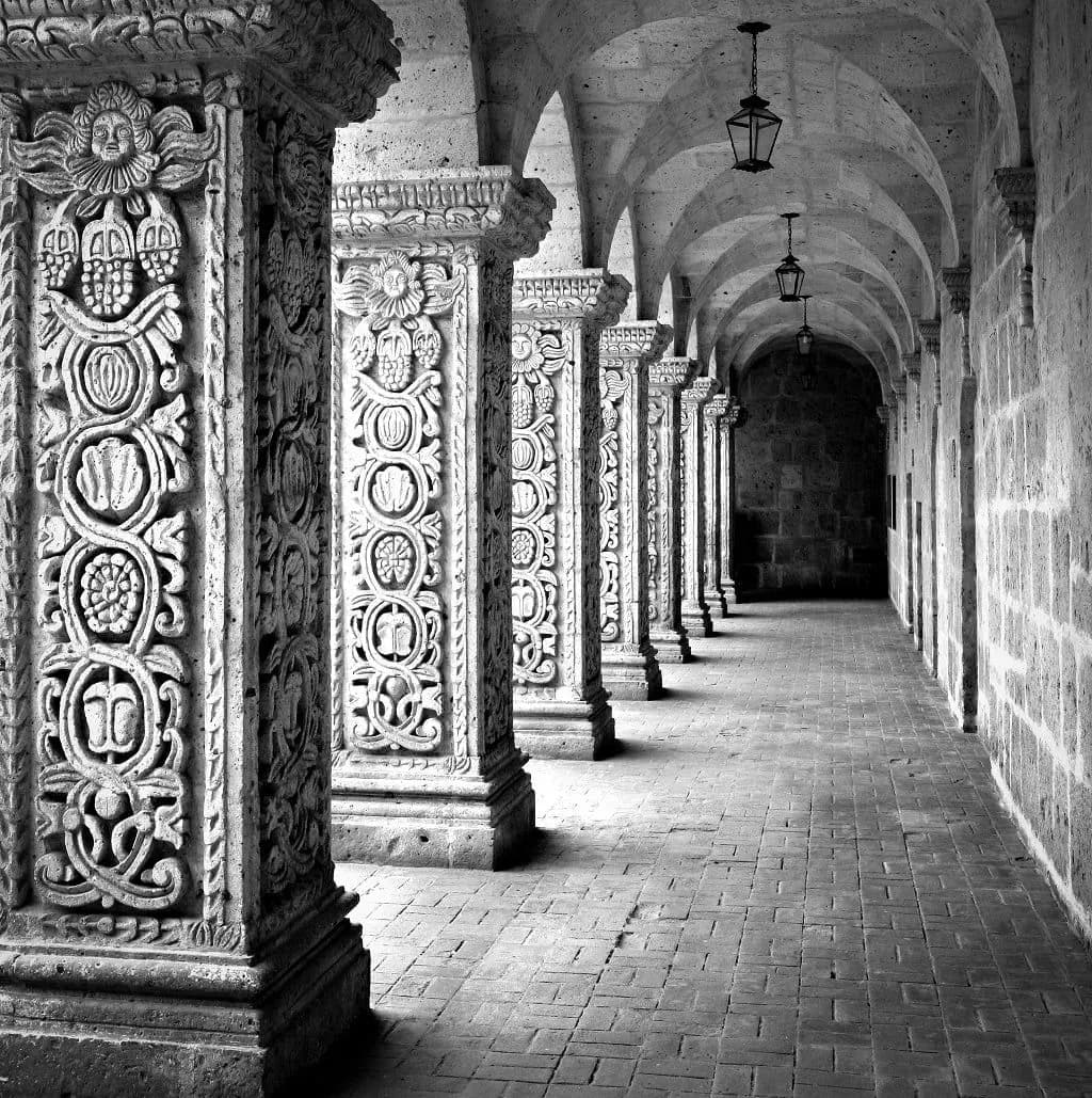 Carved stone columns along a colonial cloister, in black and white