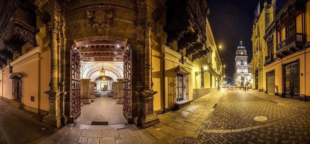 A lit colonial doorway and cobbled street in old Lima at night