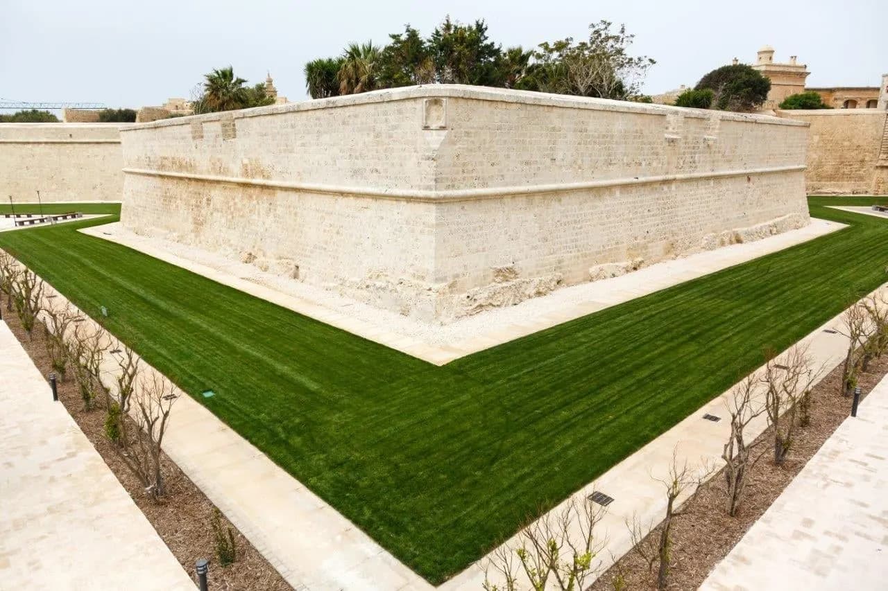 Pale limestone bastion walls above a green lawn in the old ditch