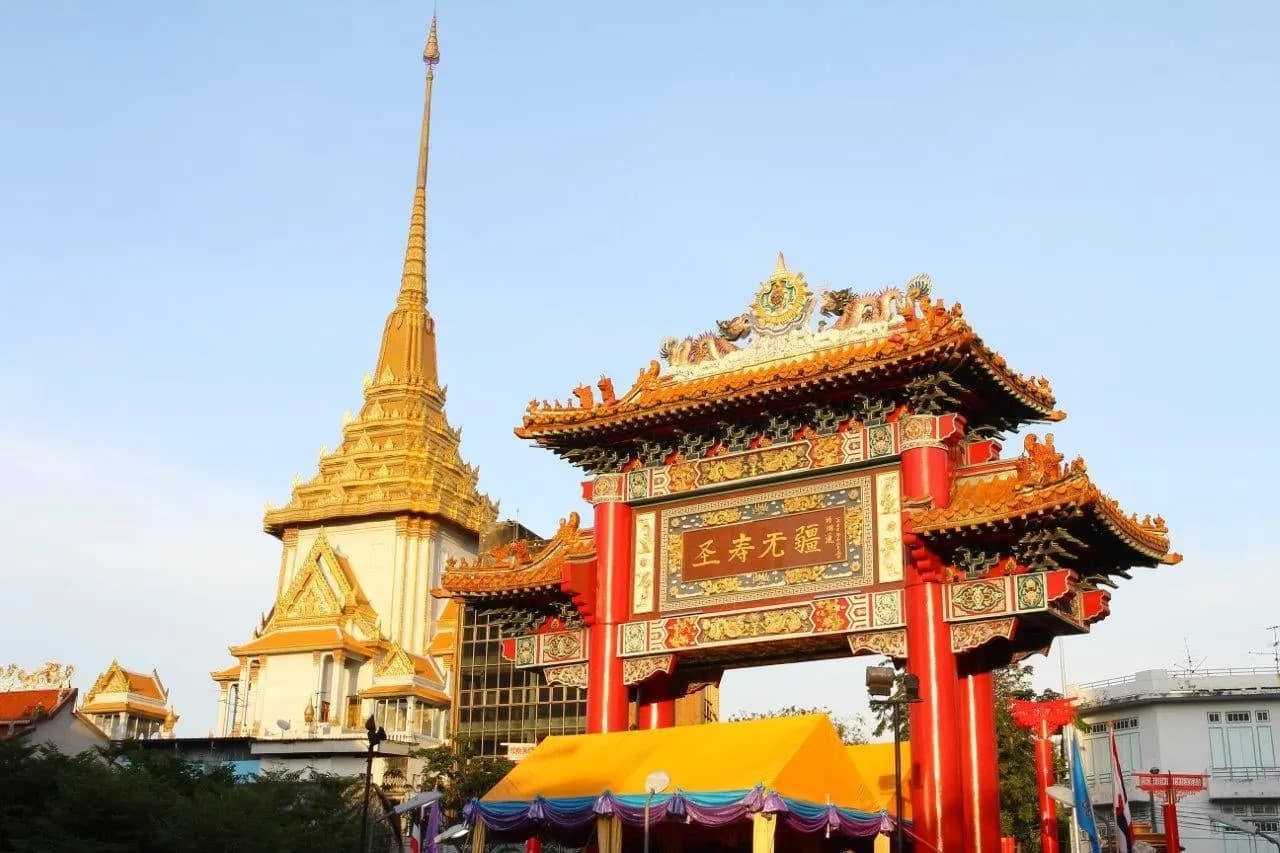The red Chinatown gate in Bangkok, with the golden spire of Wat Traimit behind