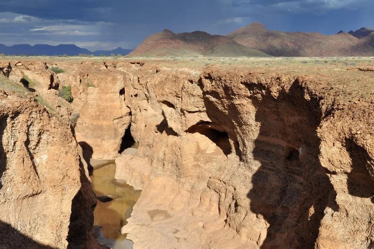 The narrow rocky gorge of Sesriem Canyon with a pool at the bottom