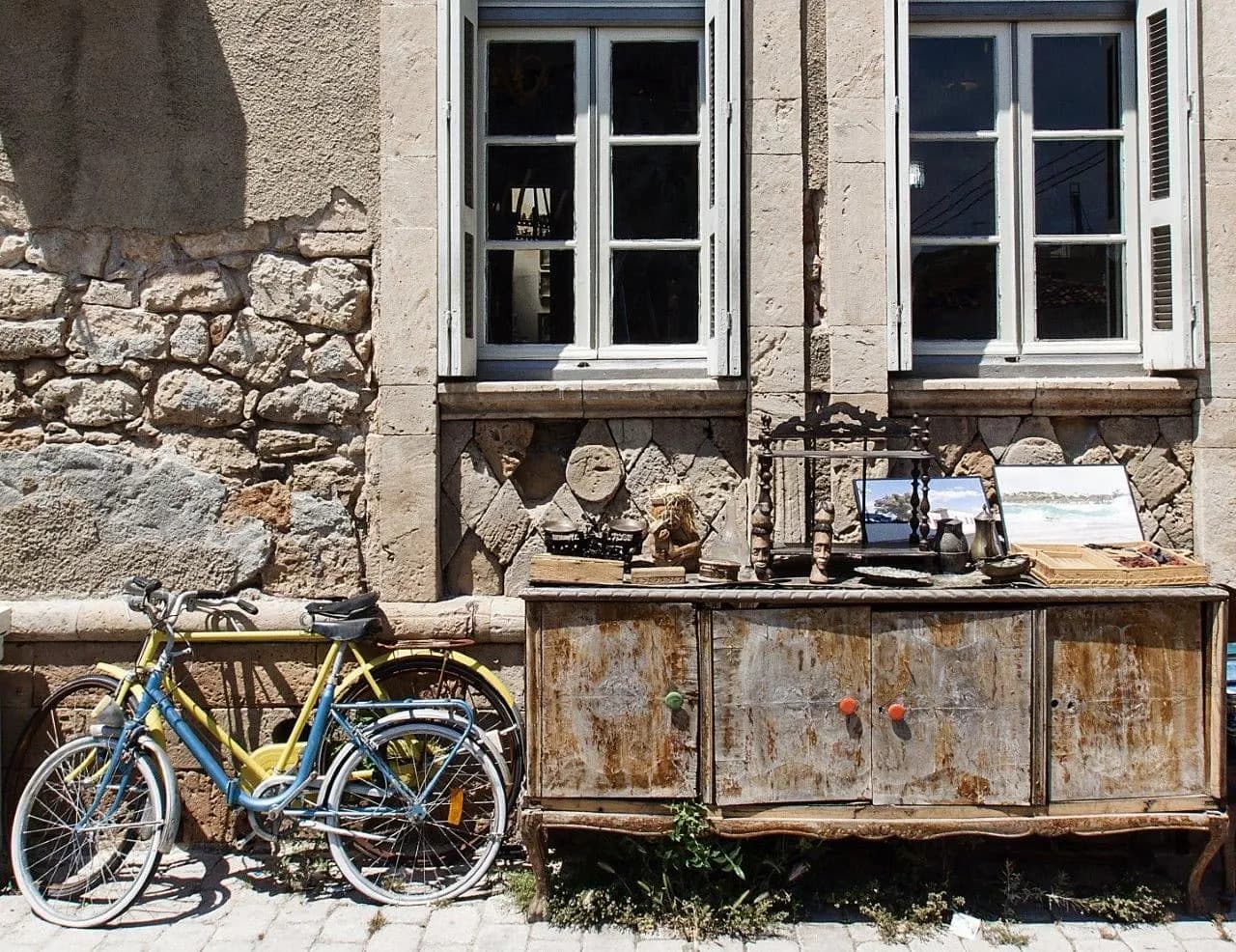 An old stone house with a bicycle and a weathered wooden counter