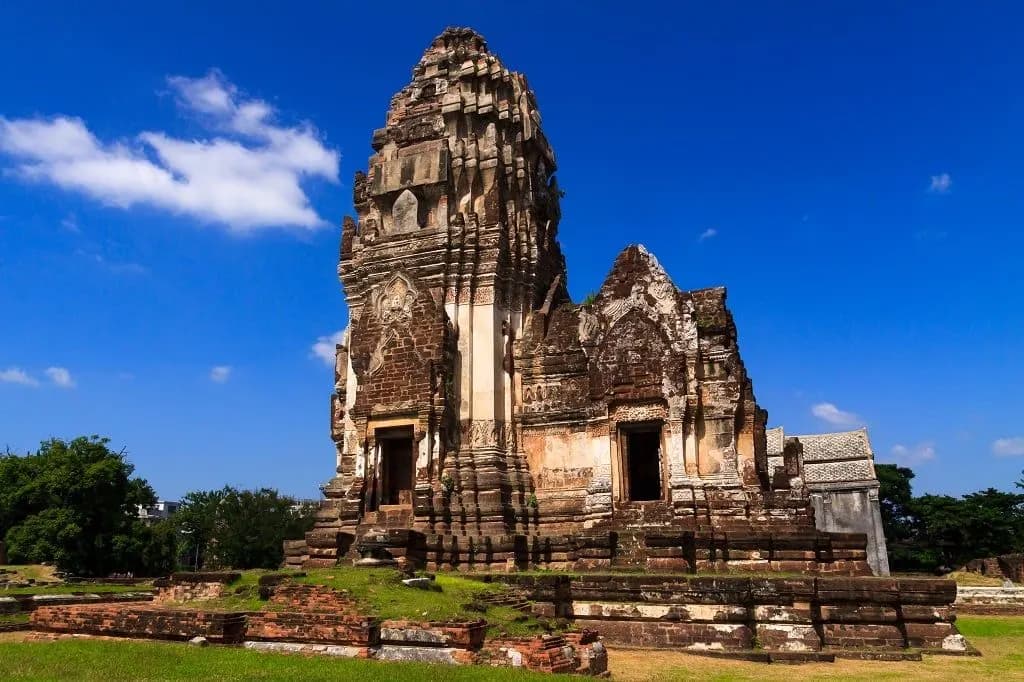 A weathered Khmer-style stone prang under a blue sky