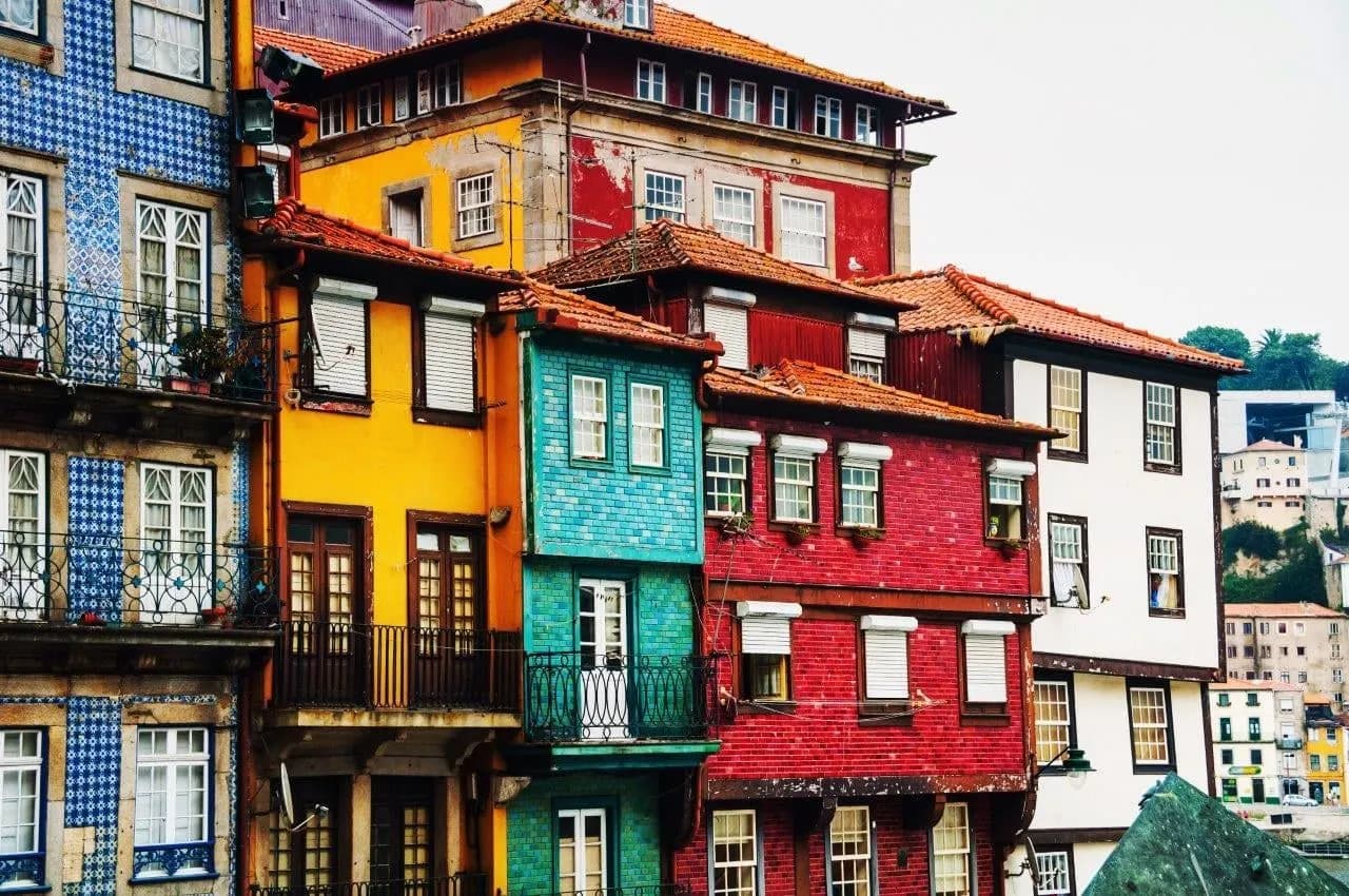 Tall tiled houses in yellow, red and green along a Porto street