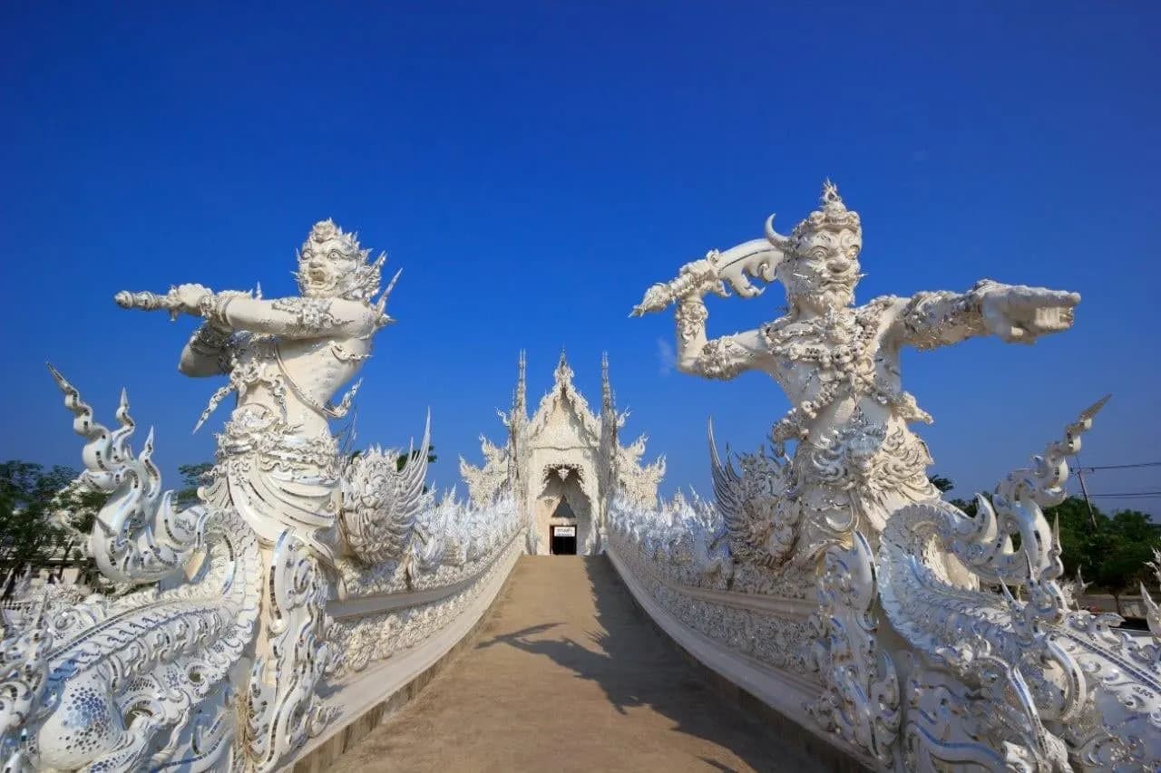 White guardian statues lining the bridge into Wat Rong Khun