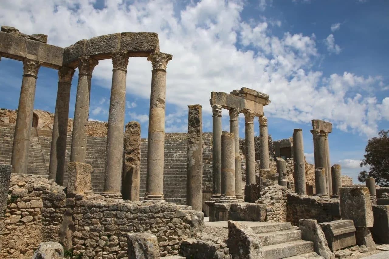 Standing Roman columns and stone walls at an ancient site under a blue sky