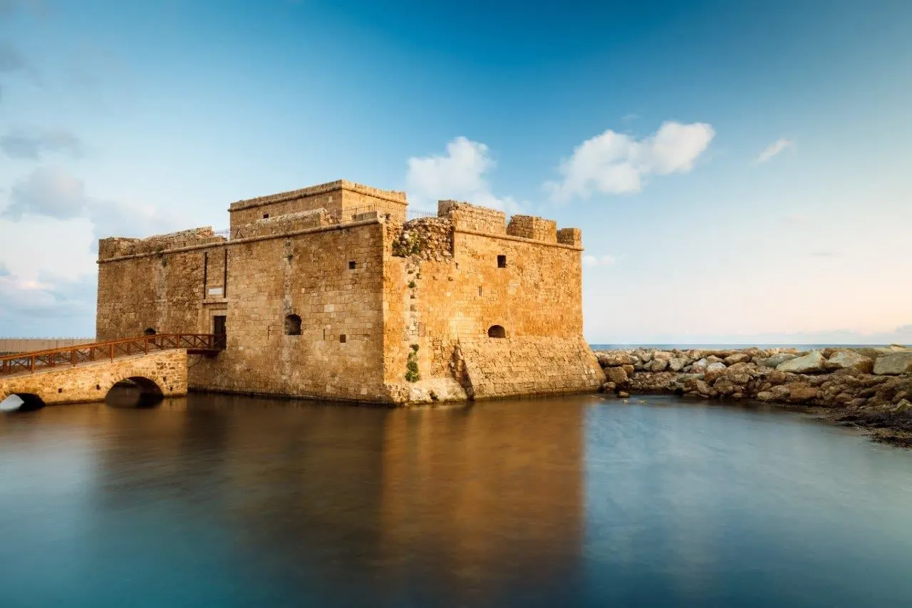 A stone fort reflected in still harbour water