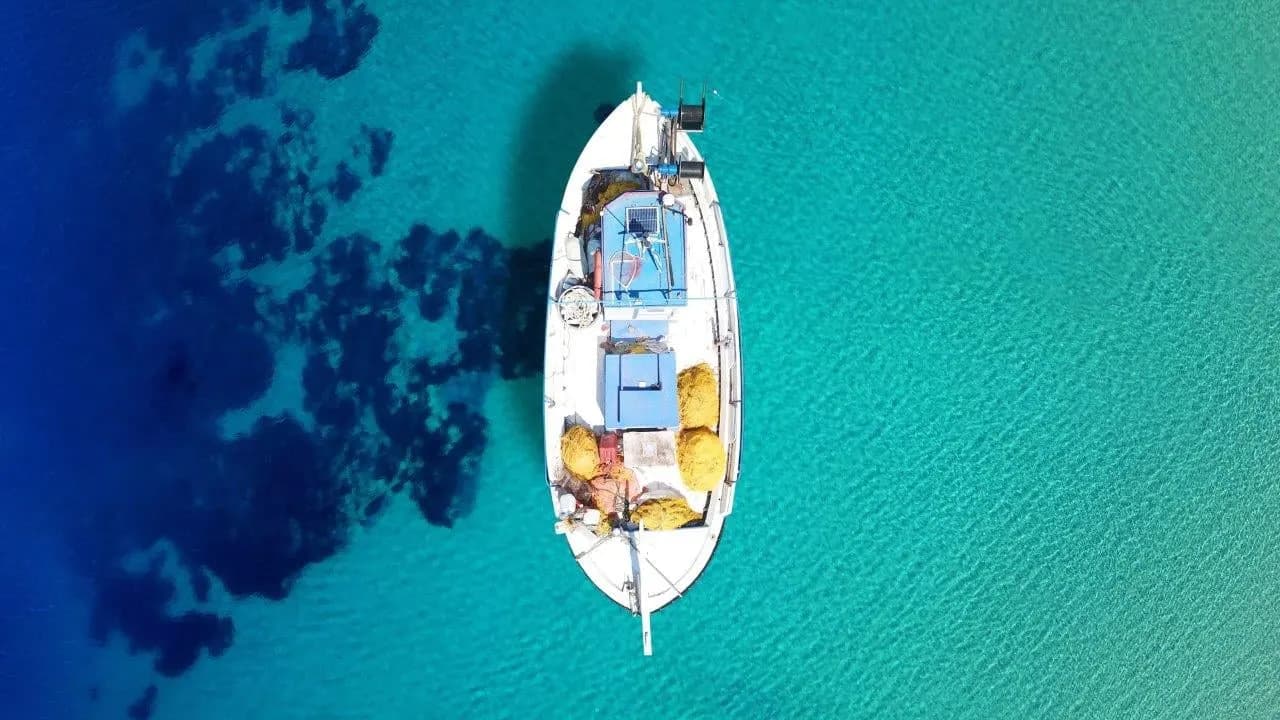 A small wooden fishing boat seen from above on turquoise water