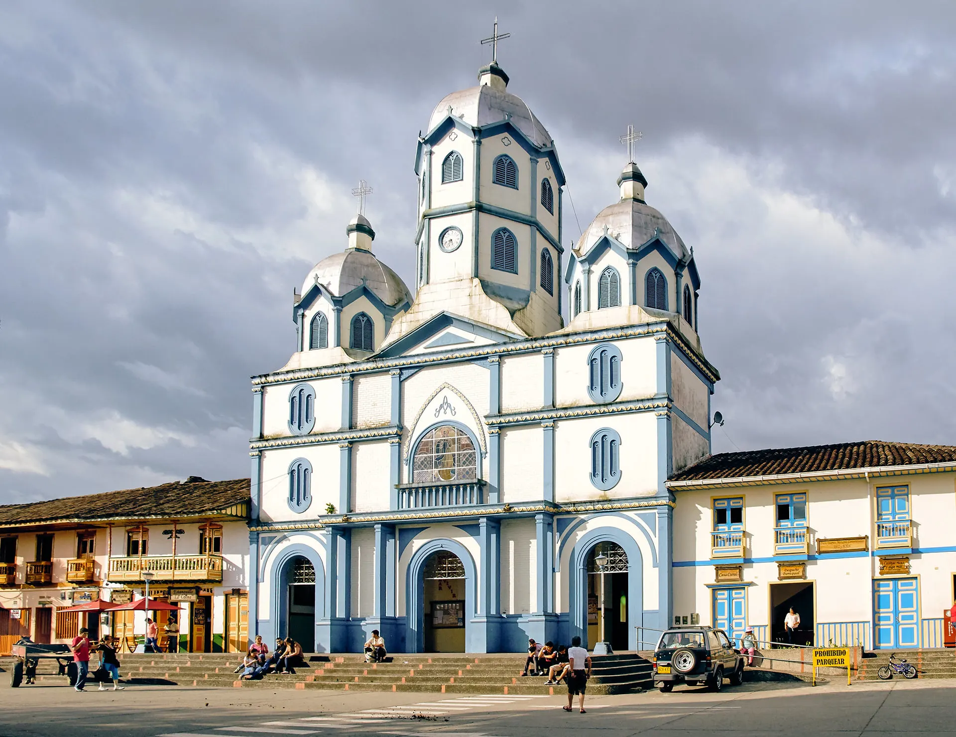 A blue and white church with three towers on a town square